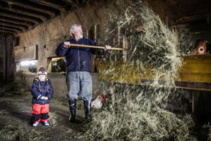 Urnaesch, Appenzell Ausserrhoden, Schweiz, 25. Februar 2009 - Hansueli Alder mit Enkelkind Ueli im Stall bei den Kuehen. 

Photo by Daniel Ammann