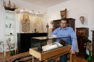 Zuerich, Schweiz,10. Maerz 2008 - Rolf Wegmueller putz im Wohnzimmer seiner Agyptischen Sammlung den Glasdeckel der Kindermumie die er vor der Kehrichtverbrennung gerettet hat.

Photo by Daniel Ammann